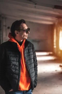 Guy in a dark jacket and orange sweatshirt posing Stock Photos