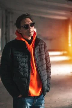 Guy in a dark jacket and orange sweatshirt posing Stock Photos