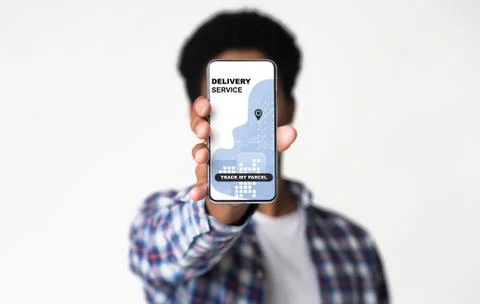 Guy demonstrating smartphone with package track app on white background Fotos Stock