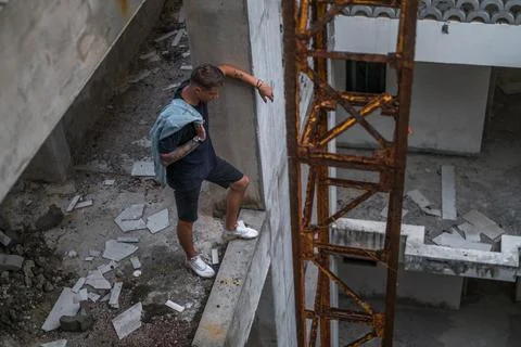 Guy in a denim jacket stands at an old construction site and looks down Stock Photos