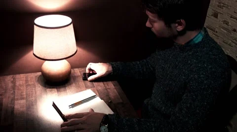 The guy at the desk with a smartphone pen writes in notebook Stock Footage 56240787