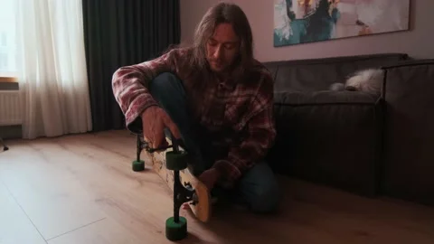 A guy disassembles the longboard and takes off the wheel. Stock Footage 238480248