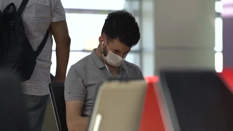 Guy in disposable face mask sits on large waiting room chair Video stock 145572305