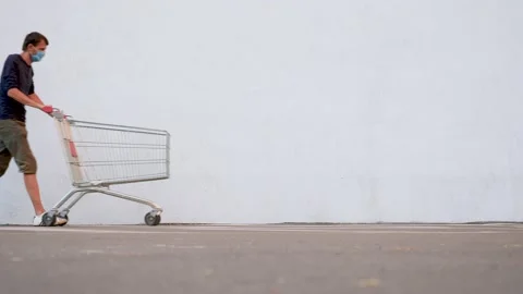 Guy in a Disposable Facemask Focused on the Phone Goes Near the Store. Shopping Stock Footage 141154642