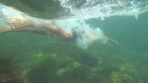 Guy dives under the water Stock Footage 99938802