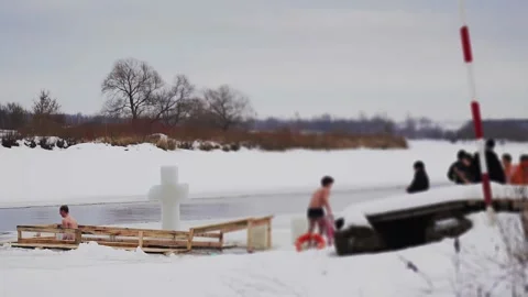 Guy diving into ice hole and blesses oneself, feast of Epiphany in winter Stock Footage 295106251