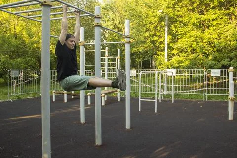 A guy does an exercise on a horizontal bar in the park. The concept of sports Stock-Fotos