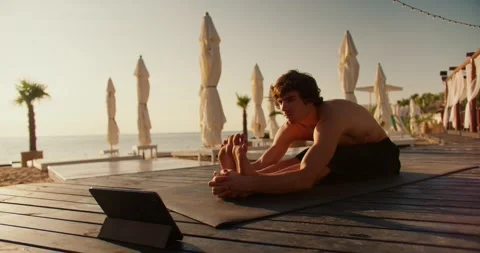 The guy does the stretch following the video on the tablet. Online stretching Stock Footage 249844075