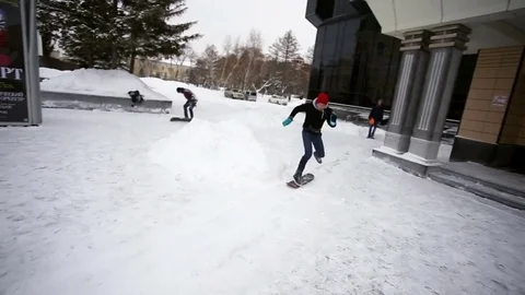 Guy does the trick from the steps on snow skate Stock Footage 77203827