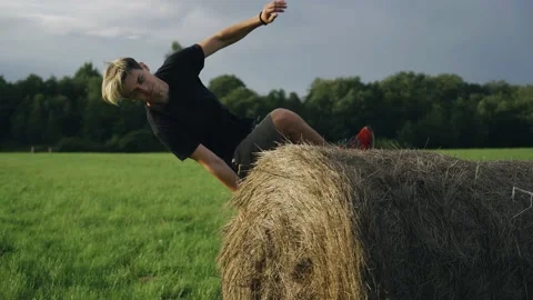 A guy does tricks and flips near a haystack in a field in the fresh air Stock Footage 158127496
