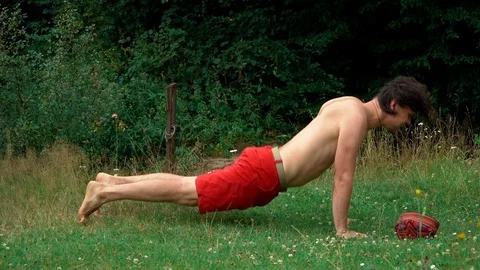 The guy does yoga on the grass against the trees. Yoga classes in nature, in the Video stock 92803626