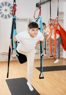 Guy doing aerial pilates exercises in suspended hammock Stock Photos