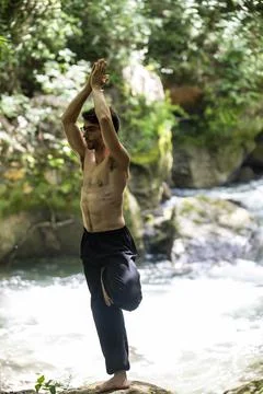Guy doing bareback yoga on the river Foto stock