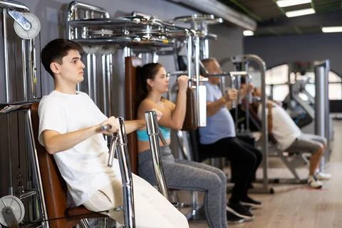 Guy doing chest presses in exercise machine in gym Stock Photos