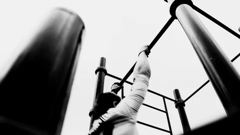 The guy is doing exercises on a horizontal bar on the Playground. Bottom view Stock Footage 129354887