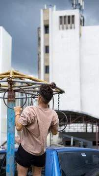 Guy doing a pull-up in a street workout, with building in the background Stock Photos