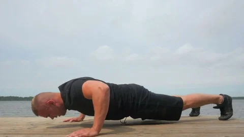 The guy doing push-ups outside at the pier in park. Video stock 83818096