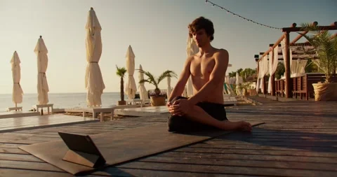 The guy is doing yoga and watching a training video on the tablet. Online sports Stock Footage 249435506