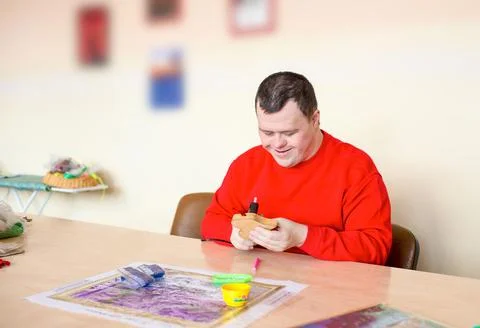 A guy with down syndrome does needlework. Stock Photos
