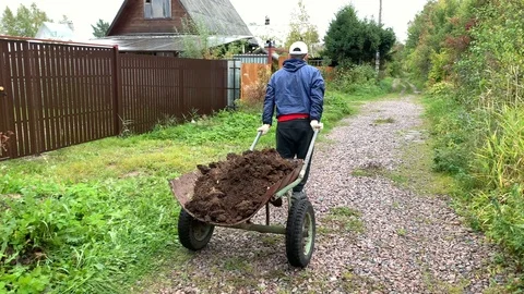 The guy drags a wheelbarrow with the ground. Stock-Footage 116649217