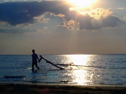 The guy drags the windsurf on a sunset Stock Photos