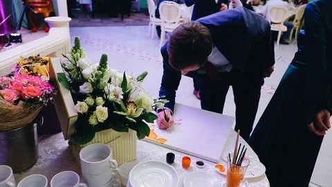 The guy draws with a brush watercolor on a white canvas. The view from the side. Stock Footage 113483535