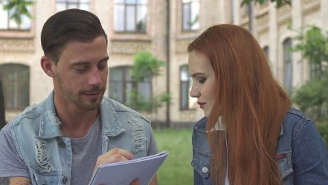 Guy draws something in his exercise book on campus Stock Footage 79673164