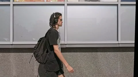 Guy  with dreadlocks calmly passes along the building Stock Footage 130669397