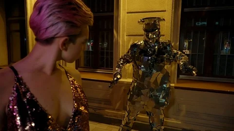 Guy dressed in extravagant mirror suit is waving hands behind slim blonde woman 스톡 동영상 93000059