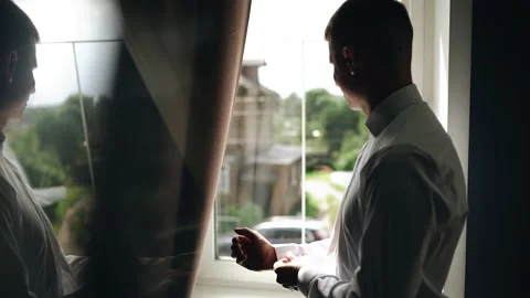 The guy dresses for a meeting standing in front of the window Stock Footage 166062144