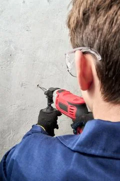 Guy drilling a hole in the wall with a drill, vertical shot Stock Photos