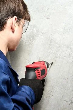 Guy drilling a hole in the wall with a drill, vertical shot Stock Photos