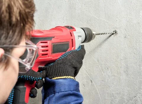 A guy is drilling a hole in the wall with an electric drill Stock Photos