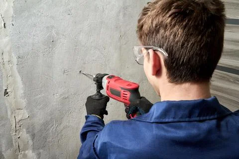 The guy drills a hole in the wall with a drill Stock Photos