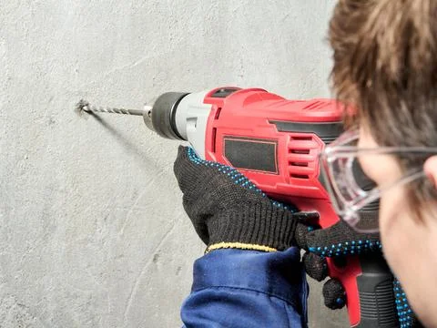 The guy drills a hole in the wall with a drill Stock Photos