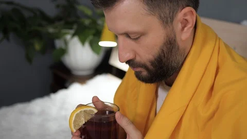 Guy is drinking black tea. Attractive young man is ill and drinks tea with lemon Stock-Footage 125296487