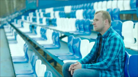 Guy drinking from the bottle on the stadium tribune Stock Footage 63842300