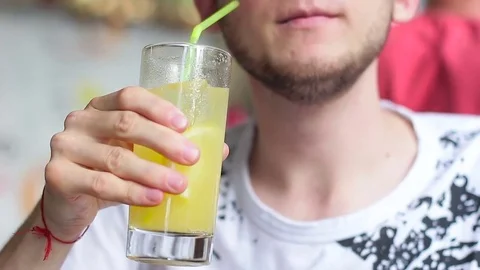 A guy drinking lemonade in a cafe on the street Stock Footage 77627599