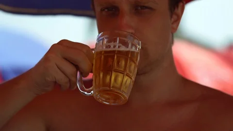 Guy drinks beer on the beach Stock Footage 126842794