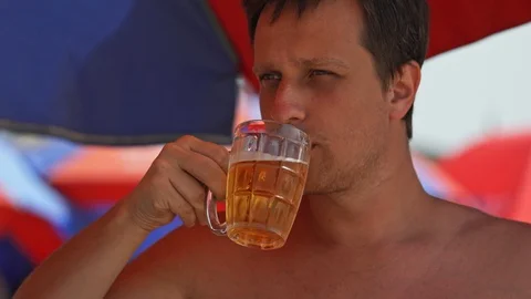 Guy drinks beer on the beach Stock Footage 126842877