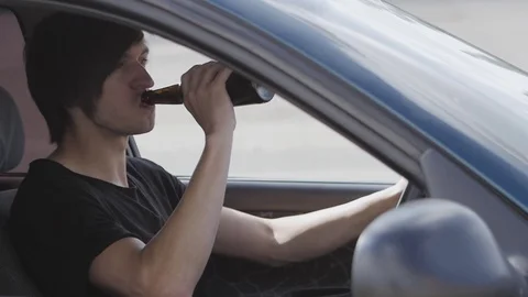 Guy drinks beer while driving a car. Drunk driver Stock Footage 75497091