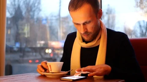 The guy drinks coffee and looks into the phone 動画素材 102545866