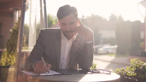 The guy drinks delicious coffee.An elegant man writes texts with a pen. Stock Footage 187021953