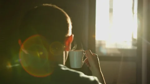Guy drinks hot coffee early in the morning at sunrise Stock Footage 129987891