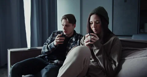 A guy drinks a hot drink with his girlfriend and tries to relax after a quarrel Stock Footage 305786511