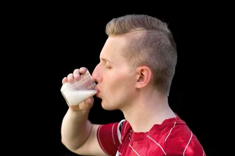 The guy drinks milk on a black background. Organic milk in the guy's hand. Ha Fotos de archivo