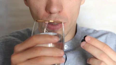 The guy drinks pills and drinks them water Stock Footage 97895419