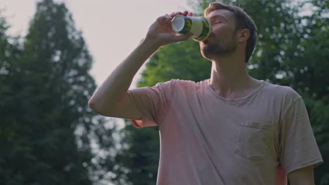 The guy drinks in the summer. The young man was enjoying life Stock Footage 157428015