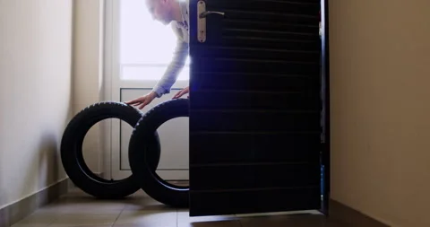 Guy driver drags rubber tires out of apartment into corridor Stockbeeldmateriaal 294602501