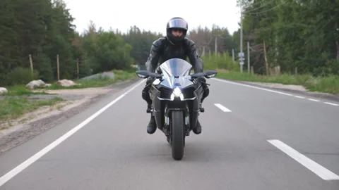 Guy driving bike during trip. Motorcyclist travel at motorcycle on rural road Stock Footage 299565321
